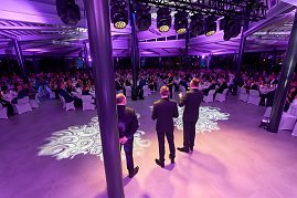 Bühnenansicht mit Rednern vor großem Publikum bei Gala-Event.