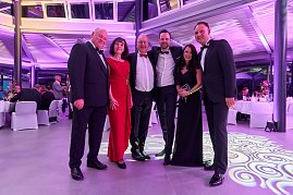 Sechs elegant gekleidete Gäste posieren gemeinsam im festlich beleuchteten Eventsaal.