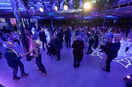 Die Tanzfläche ist eröffnet: Zahlreiche Gäste tanzen in eleganter Abendgarderobe unter stimmungsvoller blauer Beleuchtung.