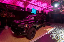 Ein schwarzer Pickup wird als Highlight-Fahrzeug inszeniert: Auf einer leicht erhöhten Präsentationsfläche steht er unter intensiver pinker Eventbeleuchtung. Lichtprojektionen auf dem Boden.