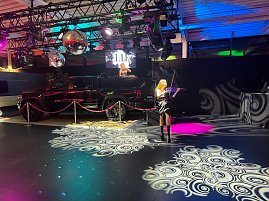 Eine eindrucksvolle Show-Inszenierung: Eine Violinistin performt live auf der Fläche, während im Hintergrund eine DJane auf einer erhöhten Bühne auf einer RAM Ladefläche auflegt.