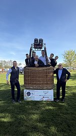 Mehrere M&auml;nner posieren f&uuml;r ein Foto in und um einen Ballonkorb