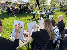Mehrere Personen sitzen hinter Staffeleien und malen mit dem Pinsel, z.B. Blumen oder B&auml;ume