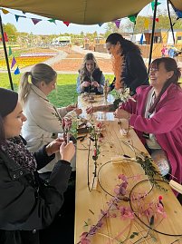 Einige Frauen basteln Trockblumenkr&auml;nze.