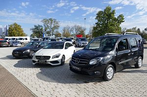 Mehrere schwarze und weiße Mercedes ‚Junge Sterne‘ Gebrauchtwagen, darunter Limousinen und ein Hochdachkombi, auf einem gepflasterten Autohaus-Areal bei sonnigem Wetter.