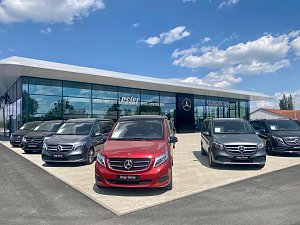Mercedes-Benz Autohaus Peter in Lutherstadt Wittenberg mit moderner Glasfassade, davor mehrere �Junge Sterne� Vans in verschiedenen Farben, blauer Himmel mit wei&szlig;en Wolken.