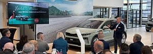 Ein Referent spricht vor einem Publikum im �koda-Autohaus. Neben ihm steht ein neuer �koda Elroq. Links ein Bildschirm mit der Begr&uuml;&szlig;ungsfolie Herzlich Willkommen zum �KODA Unternehmerfr&uuml;hst&uuml;ck.