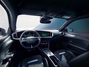 Innenraum des Opel Mokka Electric mit modernem digitalen Cockpit, gro&szlig;em zentralen Infotainment-Bildschirm und Lederlenkrad, Blick vom Fahrersitz nach vorn.