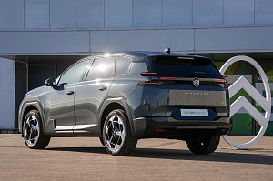 Schr&auml;g-hinten-Ansicht des neuen Citro&euml;n C5 Aircross vor einem Geb&auml;ude mit gro&szlig;em Citro&euml;n-Logo.