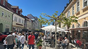 Belebte Fu&szlig;g&auml;ngerzone in Heiligenstadt bei sonnigem Wetter. Zahlreiche Menschen schlendern zwischen den farbigen Altstadth&auml;usern, im Vordergrund Caf&eacute;tische mit Sonnenschirmen.