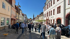 Fu&szlig;g&auml;ngerzone in Heiligenstadt voller Menschen bei strahlendem Sonnenschein. Rechts Caf&eacute;s mit wei&szlig;en Sonnenschirmen, links bunte Altstadth&auml;user.