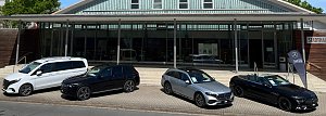 Vor der Stadthalle Wittenberg sind vier Mercedes-Benz-Fahrzeuge in einer Reihe ausgestellt: ein weißer Van, ein schwarzer SUV, ein silberner Kombi und ein schwarzes Cabriolet mit offenem Verdeck. Rechts steht eine schwarze Fahne mit dem Logo Autohaus Peter.