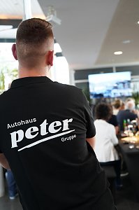 Ein Mitarbeiter der Autohaus Peter Gruppe mit R&uuml;ckenansicht w&auml;hrend des s&uuml;dafrikanischen Abends in Heiligenstadt, im Hintergrund sitzen G&auml;ste an festlich gedeckten Tischen