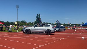 Einfahrt der Sportstars beim Leichtathletik-Meeting Anhalt 2025: Ein silberner Mercedes-Benz SUV des Autohauses Peter f&auml;hrt &uuml;ber die rote Laufbahn, ein Sportler winkt aus dem ge&ouml;ffneten Schiebedach. Dahinter stehen weitere Fahrzeuge und Eventfahnen.