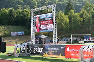 Gro&szlig;e LED-Leinwand im Stadion k&uuml;ndigt das Internationale Nordth&uuml;ringer Leichtathletikmeeting am 15. August 2025 in Sondershausen an. Davor Werbebanner verschiedener Sponsoren und Zuschauer im Hintergrund.