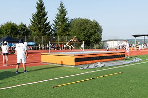 Athletin &uuml;berspringt im R&uuml;ckw&auml;rtssprung die Hochsprunglatte. Kampfrichter und Zuschauer beobachten den Versuch.