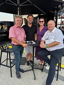 Gruppenfoto am Mercedes Cube: Centerleiter Marko Wuttke, Gesch&auml;ftsf&uuml;hrer Alexander K&auml;stner, Gesch&auml;ftsf&uuml;hrerin Christina Dost und Seniorchef Helmut Peter stehen bzw. sitzen um einen Stehtisch unter einem Sonnenschirm. Auf dem Tisch liegen Prospekte und ein Modellauto.