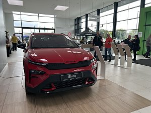 Ein roter �koda Elroq steht im Ausstellungsraum des Autohauses Autowelt Peter. Im Hintergrund stehen und unterhalten sich mehrere Besucher, daneben befinden sich Infost&auml;nde und ein Bereich mit Sitzgelegenheiten.