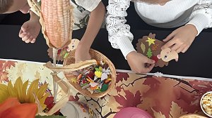 Kinder basteln im Autohaus Autowelt Peter herbstliche Figuren. Auf dem Tisch liegen bunte Papierbl&auml;tter und ein Korb mit Bastelmaterial, w&auml;hrend ein Igel aus Pappe mit Verzierungen gestaltet wird.
