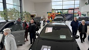 Besucherinnen und Besucher betrachten ausgestellte �koda-Fahrzeuge im Autohaus Autowelt Peter. Im Hintergrund ist eine bunte H&uuml;pfburg f&uuml;r Kinder zu sehen.