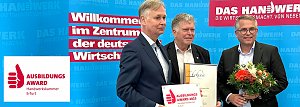 Drei Männer stehen vor einer blauen Wand mit dem Schriftzug Das Handwerk – Die Wirtschaftsmacht von nebenan. Einer hält eine Urkunde, ein anderer eine Blumenstrauß, der dritte das Schild Ausbildungsaward 2025 Handwerkskammer Erfurt. Das Bild zeigt die Übergabe des Ausbildungsawards an die Autohaus Peter Gruppe. Drei Männer stehen vor einer blauen Wand mit dem Schriftzug Das Handwerk – Die Wirtschaftsmacht von nebenan. Einer hält eine Urkunde, ein anderer eine Blumenstrauß, der dritte das Schild Ausbildungsaward 2025 Handwerkskammer Erfurt. Das Bild zeigt die Übergabe des Ausbildungsawards an die Autohaus Peter Gruppe.