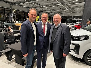 Andreas Peter, Mario Voigt und Helmut Peter stehen l&auml;chelnd nebeneinander in einem Autohaus. Im Hintergrund sind schwarze und wei&szlig;e Fahrzeuge sowie weitere G&auml;ste der CDU-Veranstaltung zu sehen.