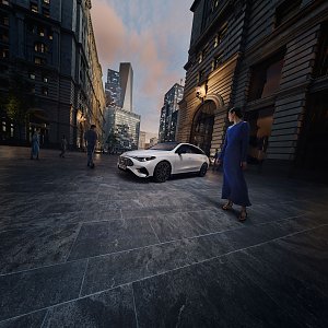 Das Bild zeigt einen weißen Mercedes-Benz CLA Shooting Brake, der auf einer breiten, nahezu leeren Stadtstraße fährt. Moderne Gebäude umgeben die Szene, das Licht wirkt weich und frühmorgendlich. Der Wagen ist seitlich zu sehen und vermittelt Dynamik sowie Eleganz.