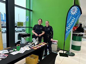 Zwei Polizistinnen stehen an einem Infostand mit Buttons und Malmaterial, daneben Banner Thüringer Polizei.