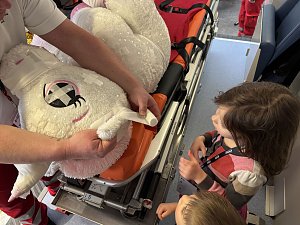 Kinder staunen, während der Rettungsdienst ein Stofftier im Krankenwagen versorgt.