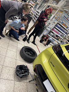 3 Frauen stehen neben einem gelben Peugeot 208, auf dem Fu&szlig;boden liegt ein Rad