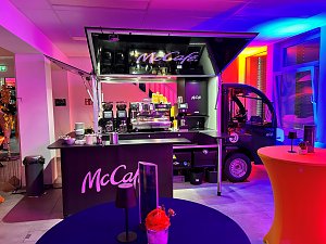 cCaf&eacute;-Kaffeebar im Eventbereich mit buntem Licht und Stehtischen.