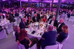 G&auml;ste sitzen an gedeckten Tischen bei Gala-Event mit stimmungsvoller Beleuchtung.