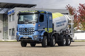 Elektrischer Betonmischer Mercedes-Benz eArocs 400 steht vor einem modernen Firmengebäude mit Bäumen im Hintergrund