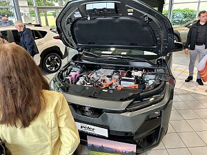 Subaru mit geöffneter Motorhaube und interessierten Personen, die hinein schauen.