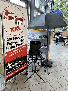 Rollup vom Angelspezi Halle mit Angelstuhl und Ausrüstung daneben.