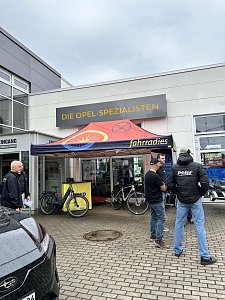 Fahrradstand vom Fahrradies Halle vor Autohaus, einige Personen daneben.