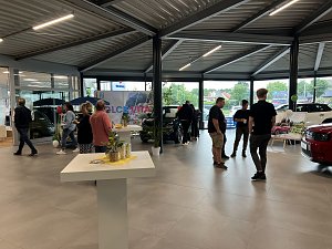 Mehrere Personen im Autohaus Showroom, im Hintergrund Fahrzeuge der Marke Fiat