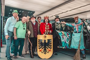 Mehrere Personen auf der Skoda-Roadshow-Bühne (4 davon kostümiert), alle schauen in die Kamera; dahinter ein bunt beklebtes Fahrzeug