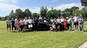 Gruppenfoto der Turnierteilnehmenden vor einer schwarzen Mercedes-Benz Limousine auf dem Golfplatz.