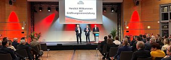 Auf einer gro&szlig;en Leinwand steht Die Automobilmesse Erfurt 2025 ist er&ouml;ffnet!. Davor sprechen drei M&auml;nner (rechts Helmut Peter) auf einer B&uuml;hne, w&auml;hrend zahlreiche Besucher im Saal zuh&ouml;ren. (Autohaus Peter)