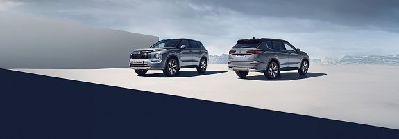 Das Bild zeigt den neuen Mitsubishi Outlander. Es sind zwei silbergraue Mitsubishi Outlander abgebildet � einer von vorne, einer von hinten � vor einer weiten, hellen Landschaft.