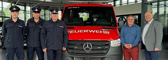 &Uuml;bergabe eines neuen Mannschaftstransportwagens an die Freiwillige Feuerwehr Urbach durch das Autohaus Peter. Vor dem roten Feuerwehrfahrzeug mit der Aufschrift �FEUERWEHR� stehen drei Feuerwehrm&auml;nner in Uniform sowie Ortsb&uuml;rgermeister Markus Volkmann und unser Gesch&auml;ftsf&uuml;hrer Helmut Peter. Das Foto wurde im Ausstellungsraum des Autohauses aufgenommen.