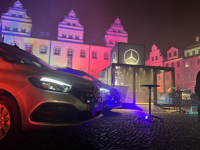 Mercedes-Benz EQT & EQV vor dem Event Cube, stimmungsvoll inszeniert mit Lichtershow am historischen Rathaus.
